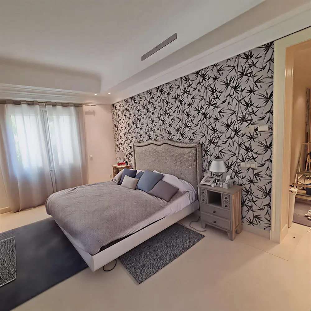 Pintor Dos Hermanas instalando papel pintado de hojas en cabecero de dormitorio moderno